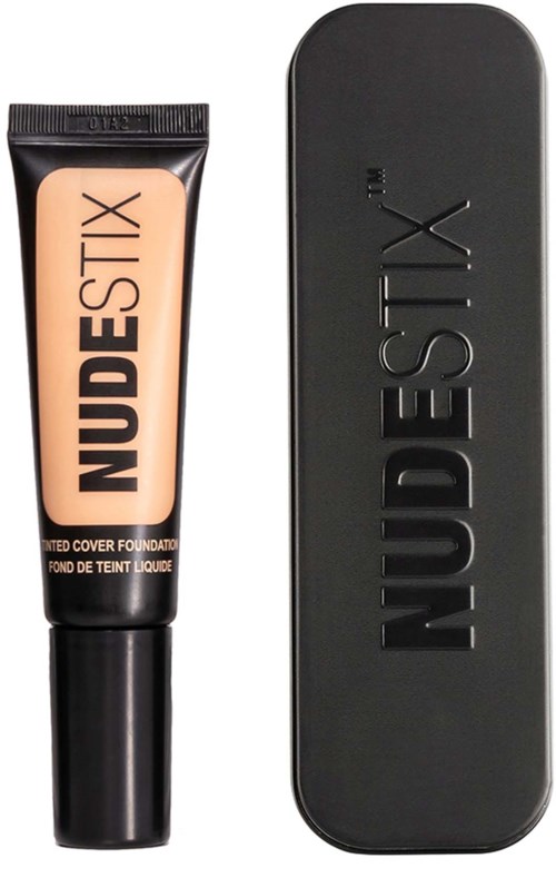 A tube of liquid foundation beside a black compact case, both labeled 'NUDESTIX' in bold letters.