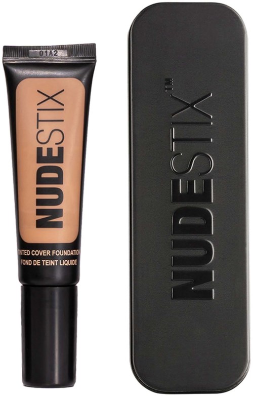 Een tube foundation en een zwarte case, allebei gelabeld 'NUDESTIX', staan op de afbeelding.