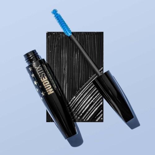 Een zwarte mascara-tube met witte sterren, blauwe mascara-wand en een zwarte getextureerde achtergrond.
