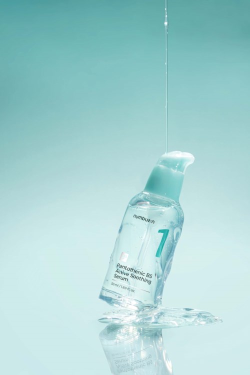 Een glazen fles met water erin, gemarkeerd met een nummer en tekst, staat op een reflecterend oppervlak.