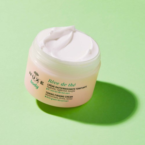A jar of moisturizing cream with white content on a green background.