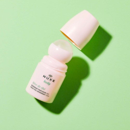 Een witte deodorantstick met een gedeeltelijk open dop, op een lichtgroene achtergrond, werpt schaduw.
