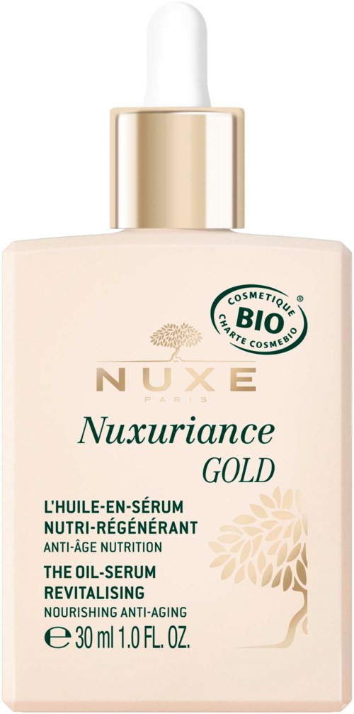 A beige bottle with a dropper cap, labeled Nuxe Nuxuriance Gold oil serum with green and gold text and a tree illustration.
