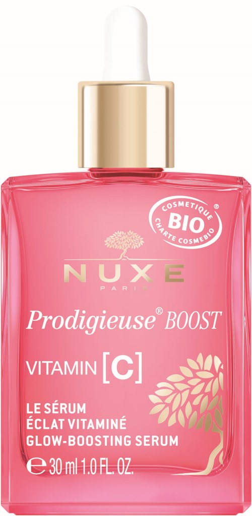 A pink glass bottle with a gold dropper cap, labeled as a glow-boosting serum with vitamin C from Nuxe Paris.