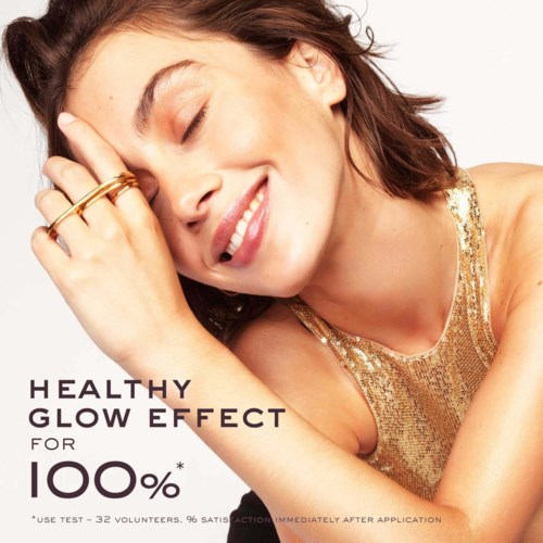A smiling woman with a radiant glow, wearing a sparkly gold top, promoting healthy skin effects.