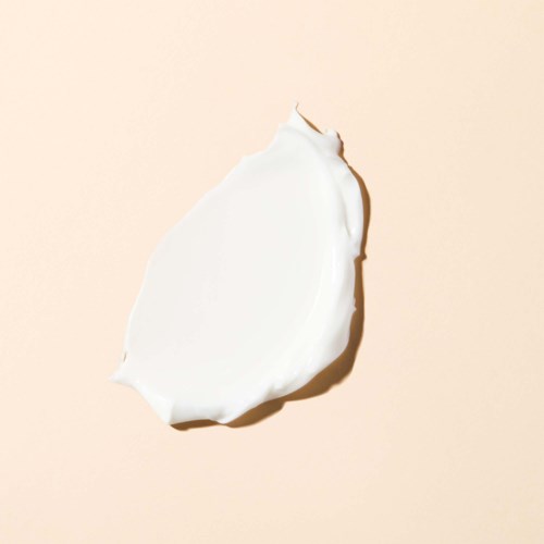 Een witte romige stip op een lichtroze achtergrond. Geen andere voorwerpen zichtbaar.
