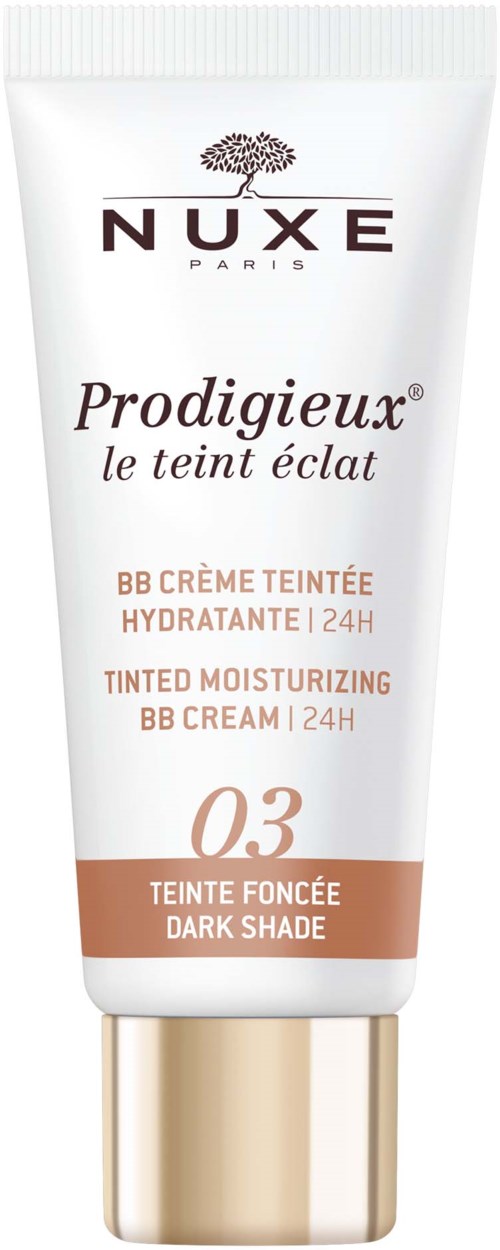 Een witte tube met goudkleurige dop, gemerkt "NUXE" met een boomlogo en tekst over getinte hydraterende BB-crème in donkere tint.