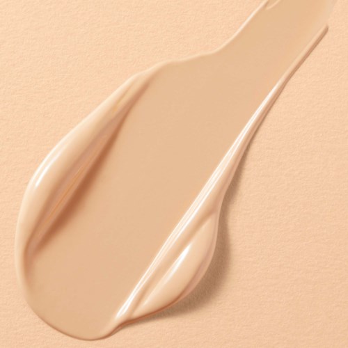 Room of lotion op een beige ondergrond, gevormd als een traantje. Gladde en glanzende textuur.