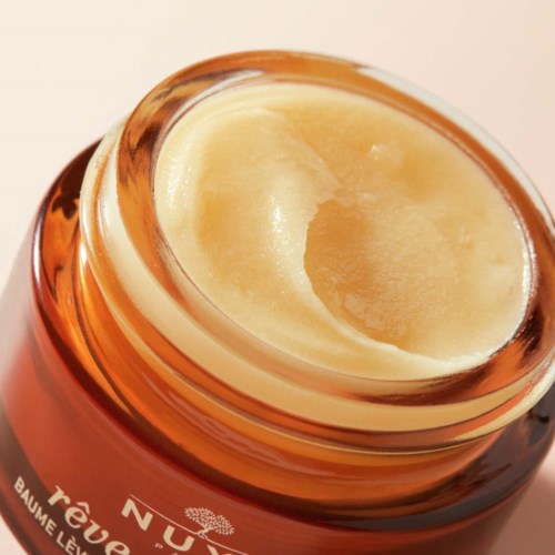 An open cosmetic jar with a creamy substance inside, showing a smooth texture and a beige color.
