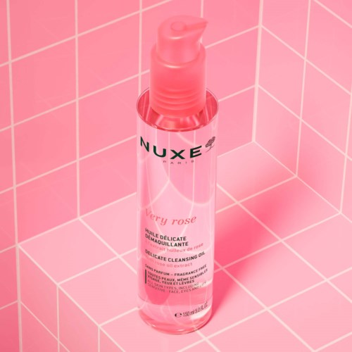 Eine rosa Flasche mit der Aufschrift 'NUXE Very Rose' auf rosa gefliester Wand, wahrscheinlich ein Hautpflege- oder Reinigungsprodukt.