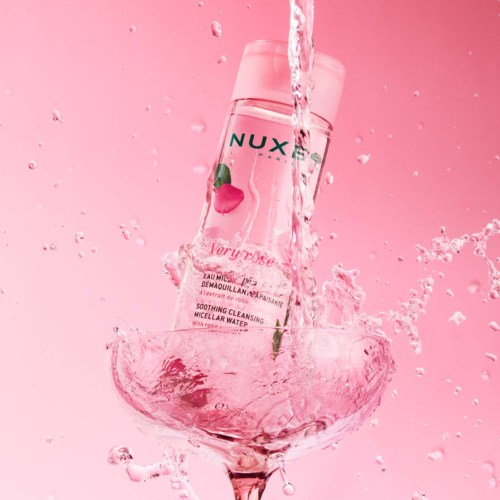 A pink bottle of NUXE Very Rose cleansing water splashes into a bowl of water.
