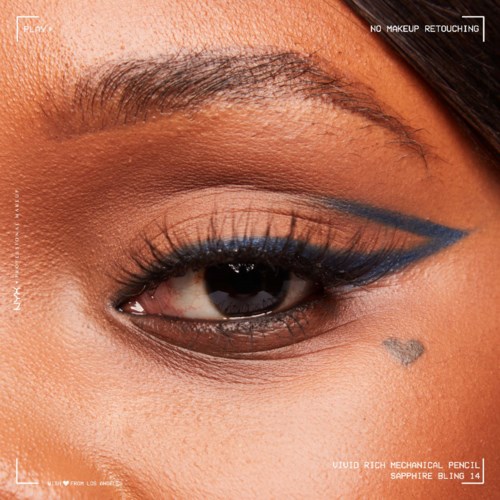 A close-up of a person's eye with blue eyeliner, well-groomed eyebrow, and textured skin near the eye.
