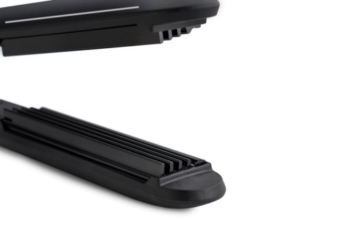 A black, rectangular, plastic object with ridges, possibly a handheld device or a tool.