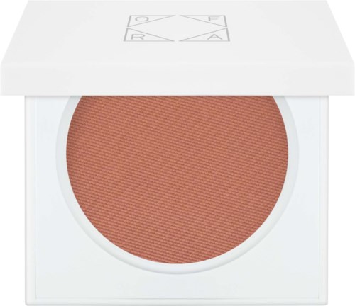 Een ronde, bruinachtige blush of oogschaduw in een witte kasmetiekdoos met deksel. De deksel heeft een logo met vier letters.
