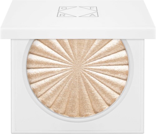 Een beige pressed highlighter in een witte verpakking met zonnestraalmotief en minimalistische doos.