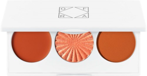 Een witte doos bevat drie ronde blush, een heeft een getextureerde perzikkleurige oppervlakte.