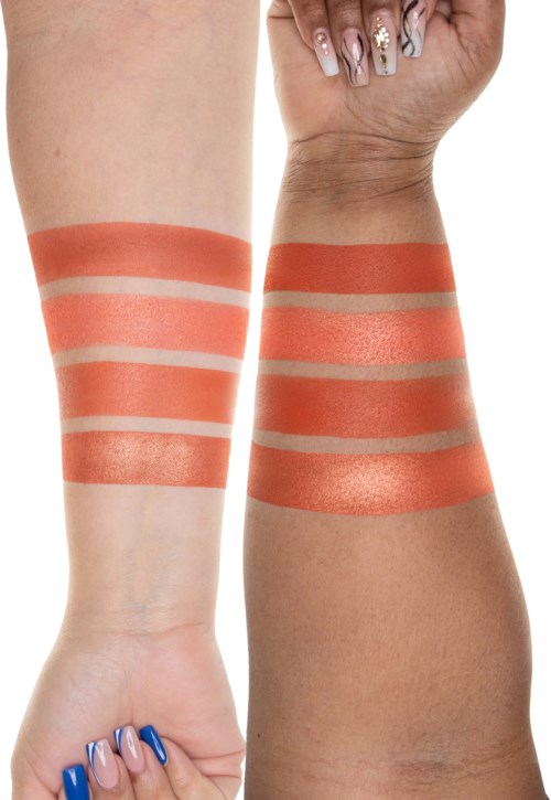 Twee armen tonen proefjes van make-up of lichaamsverf in oranje- en beige tinten, met nagels in verschillende kleuren.