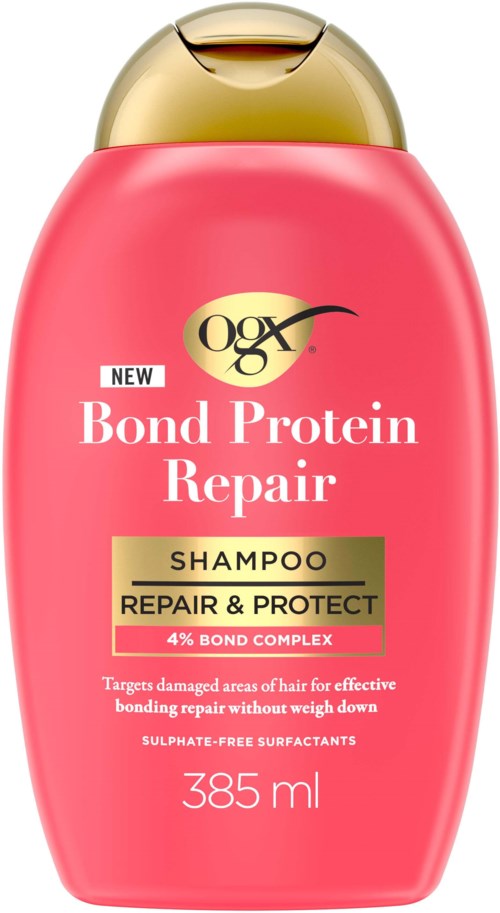 Een roze flesje van OGX Bond Protein Repair Shampoo met gouden dop, 385 ml, met label over reparatie en bescherming.