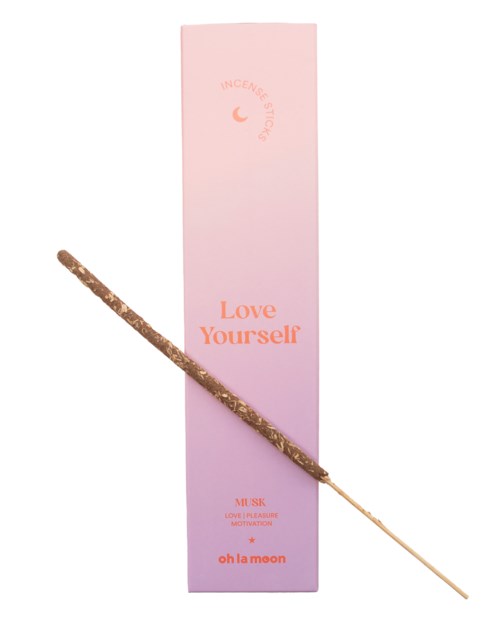 Vaaleanpunainen ja violetti laatikko, jossa lukee "Love Yourself" ja edessä pieni suitsuke.