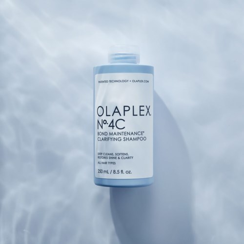 Een lichtblauwe shampoo fles met zwarte en blauwe tekst staat op een lichte, zachte oppervlak.