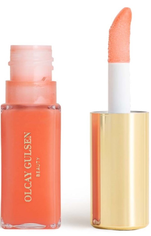 Ein korallenfarbenes Lipgloss mit Applikator in einem goldenen Gehäuse. Die Marke ist Olcay Gulsen Beauty.