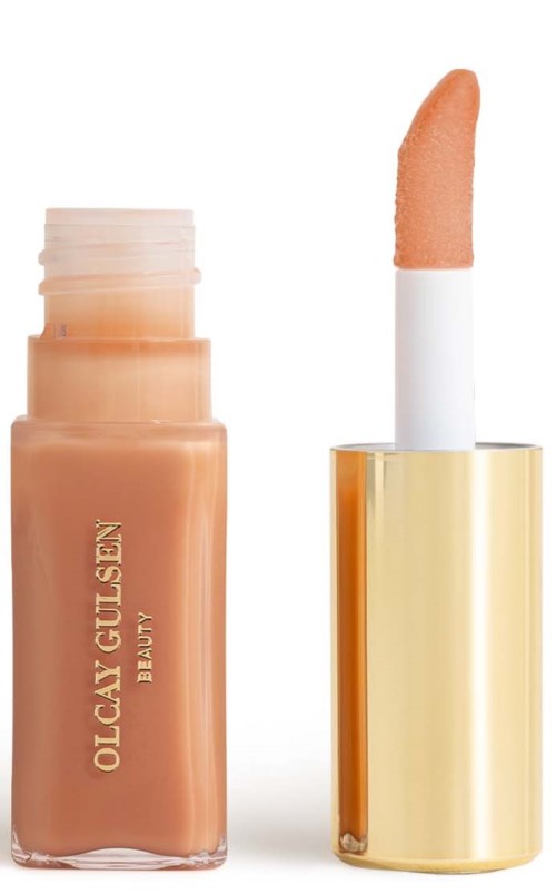 Eine beige flüssige Foundationflasche und ein Schwammapplikator mit goldener Kappe. Der Markenname steht auf der Flasche.