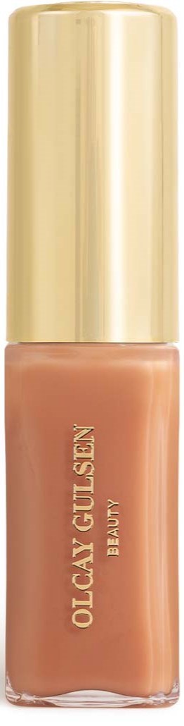 Eine Flasche Flüssigfoundations mit goldener Kappe, beschriftet "Olcay Gül Sign Beauty."