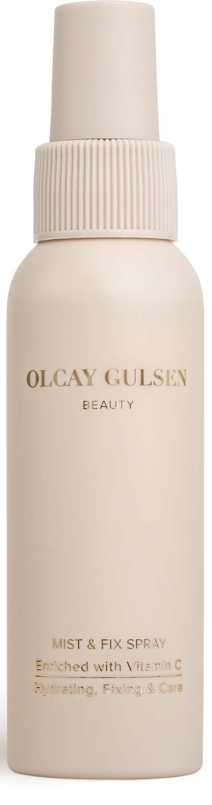 Een witte sprayfles met sproeikop, gemerkt Olcay Gulsan Beauty Mist & Fix Spray, verrijkt met vitamine C.