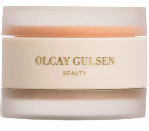 Een witte container met gouden tekst: Olcay Gulsin Beauty, gestapeld in drie lagen.