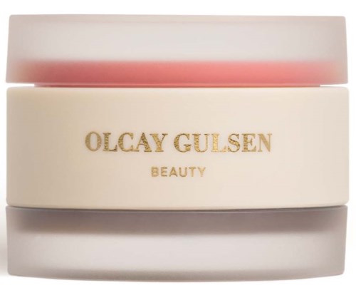 Een kleine ronde cosmeticablik met witte body en roze deksel, gemarkeerd 'OLCAY GULSEN BEAUTY' in gouden letters.