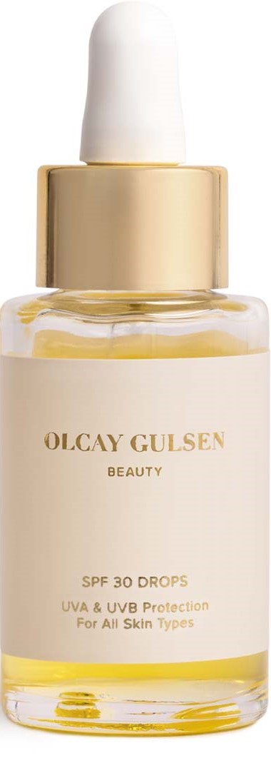 Een huidverzorgingsfles met druppelaar, met label Olcay Gulsan, biedt SPF 30 en UV-bescherming voor alle huidtypes.