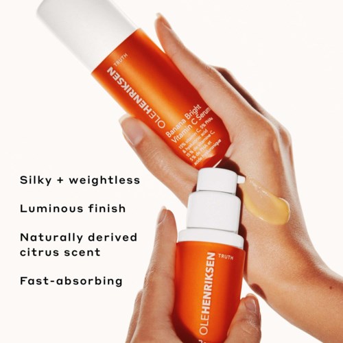 Een hand houdt oranje huidverzorgingsflessen die kenmerken zoals glanzende finish en citrusgeur tonen.