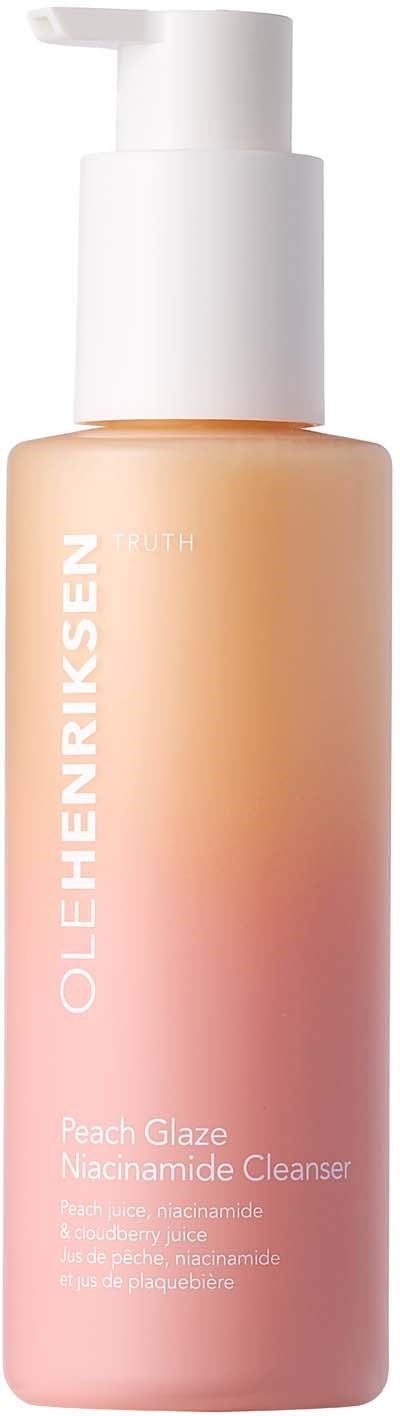 Eine pfirsichfarbene Hautpflegeflasche mit weißer Pumpe, beschriftet OLEHENRIKSEN Peach Glaze Nacinamide Cleanser.