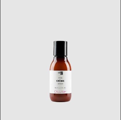 Bruine fles met stylingcrème met zwarte dop, witte label en rode tekst, staat alleen.