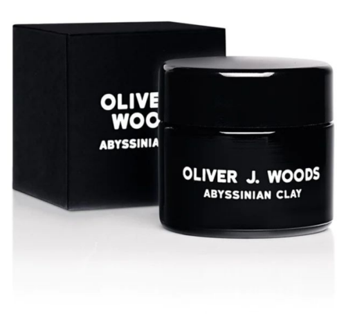 Een zwarte pot en doos met witte tekst voor Oliver J. Woods Abyssinian Clay huidverzorgingsproduct.