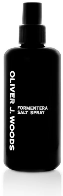 Een zwart sprayflesje met het label Oliver J. Woods Formentera Salt Spray, met een spuitmondje.