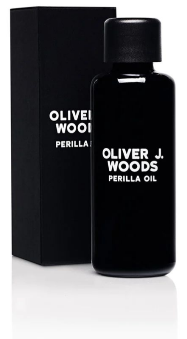 Een zwarte fles Oliver J. Woods Perilla Oil met bijpassend zwart doosje.