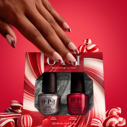 Two bottles of nail polish, one gray and one pink, are in a gift box surrounded by red and white striped candies.