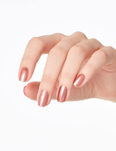 En hand med glänsande, ljusrosa nagellack på naglarna. Fingrarna är något böjda.