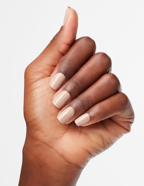 En hand med snyggt målade beige naglar visar ett tumme upp-tecken.