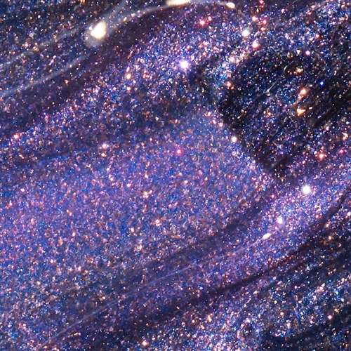 A close-up of glittering purple and blue fabric with shiny, sparkly texture and flowing folds.