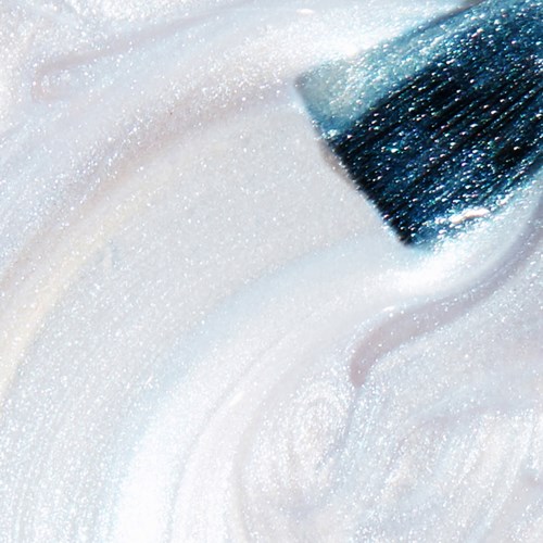 En närbild av en borste som sprider glittrande vit färg eller glitter, vilket skapar en slät, glittrande yta.