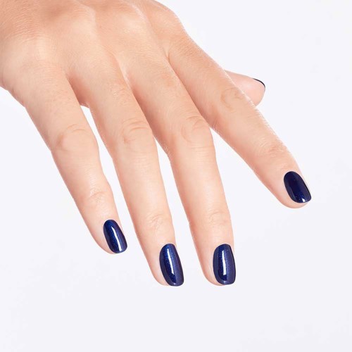 A hand with nails painted dark blue, fingers slightly spread, against a light background.