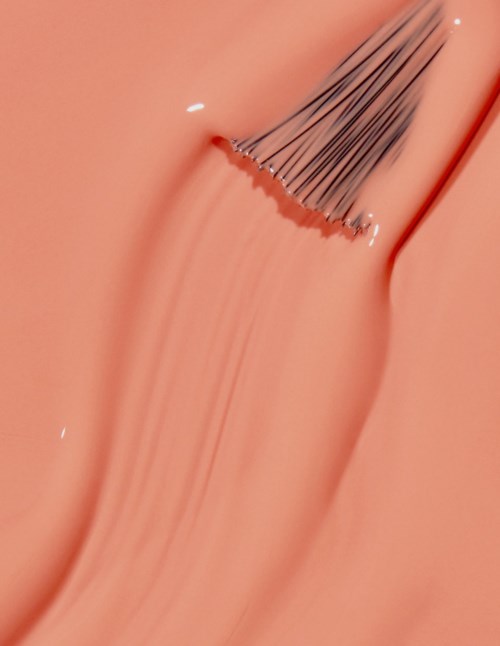 En makeupborste applicerar blush eller ansiktsprodukt på hud med en mjuk, persikofärgad ton.