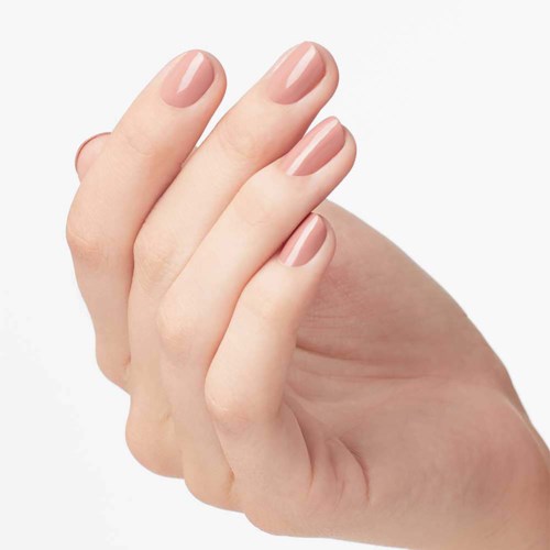 A hand with well-manicured, nude-colored nails is shown against a plain background.