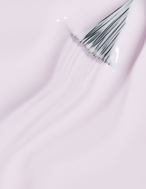 A makeup brush spreads soft pink makeup or cream smoothly on skin.
