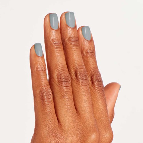 A hand with nails painted in light gray color. The skin has a warm tone. The background is plain and light.