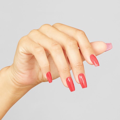 A hand with long, shiny pink nails is shown against a gray background.
