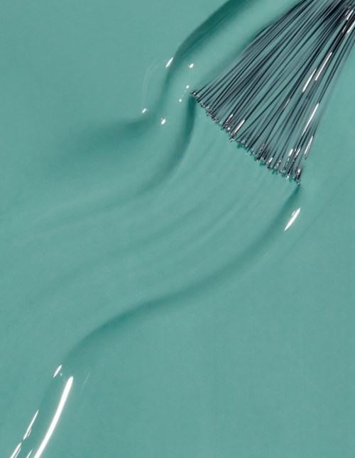 A few metal needles or pins are placed on a smooth, teal-colored surface, with some water droplets nearby.