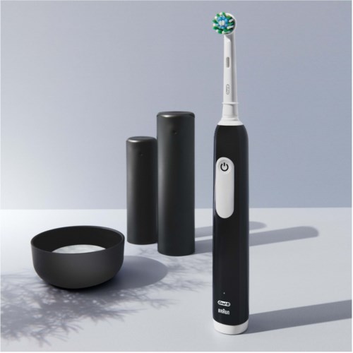 An electric toothbrush with a black base, two black battery packs, and a black bowl on a light surface.